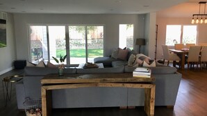 Ein modernes Wohnzimmer mit einer grauen Eckcouch, einem Holztisch und einem Essbereich mit Tisch und Stühlen.
