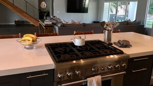 Eine moderne Küche mit Kochinsel, Herd, Backofen und einem Essbereich mit Sofa und Fernseher.