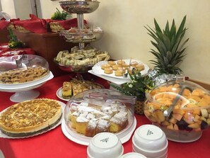 A buffet table with various food items, including pies, pastries, and fruit. - Hotel Bagli (Rimini)
