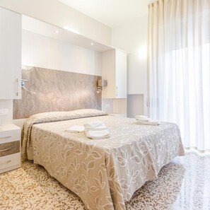 A modern hotel room with a large bed, a built-in wardrobe, and a bathroom with a shower. - Hotel Bagli (Rimini)