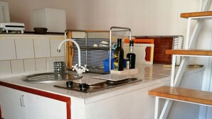 Una cocina con un lavabo, encimera y estantes de madera.