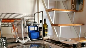 Una cocina con un lavamanos de acero inoxidable, un horno empotrado y un armario blanco con pomo.