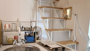 Una cocina con un lavamanos, una cafetera y una estantería de madera.