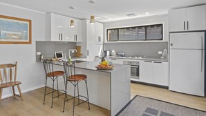 A modern kitchen with white cabinetry, a central island with bar stools, and a built-in oven.