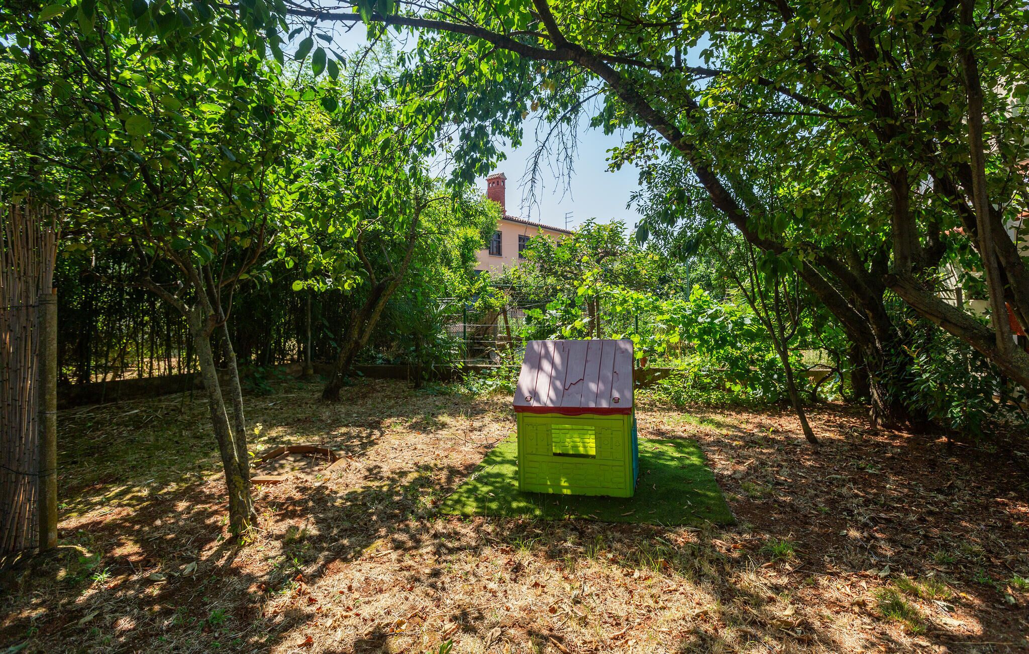 A green structure with a red roof in a wooded area.