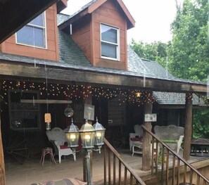 Relax on the porch with wicker chairs and a table, surrounded by trees.
