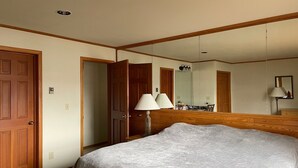 Habitación de hotel con una cama grande, cabecera de madera, un espejo, un escritorio con silla y una lámpara.