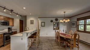 Una cocina moderna con una isla central, armarios de madera, microondas integrado y un comedor con candelabro.
