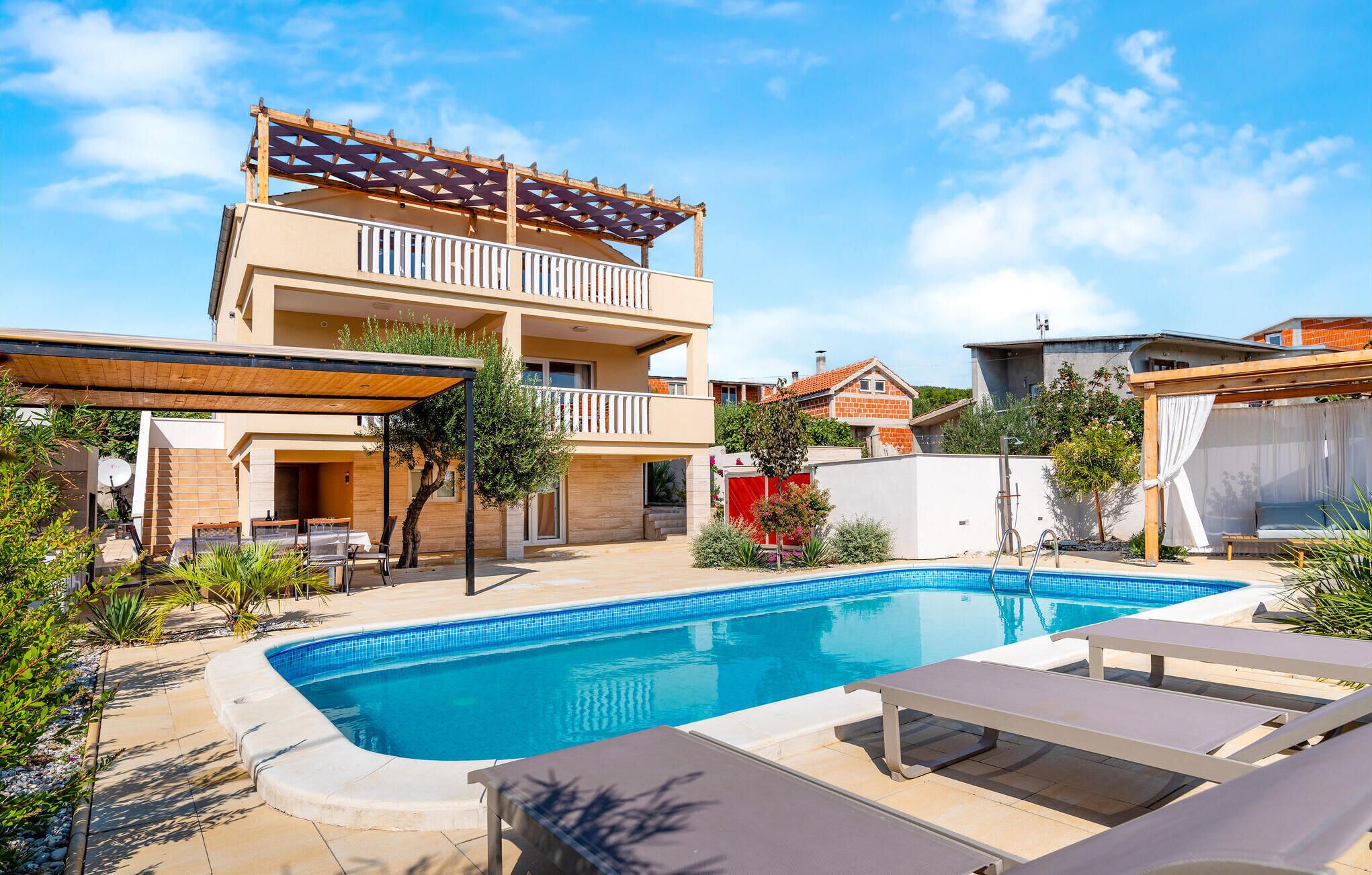 Un bâtiment à deux étages doté d’une piscine, d’un espace extérieur aménagé et d’un patio couvert.