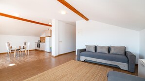 Un'ampia zona giorno con divano, tavolo da pranzo con sedie e cucina sullo sfondo.