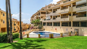 A residential building with multiple balconies, a swimming pool, and a well-maintained lawn.