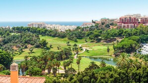 A golf course with a lake, surrounded by lush greenery and residential buildings.
