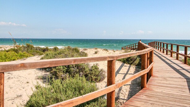 A wooden boardwalk leading to a beach with clear blue water and sandy dunes. - Stunning apartment in Santa Pola (Santa Pola)