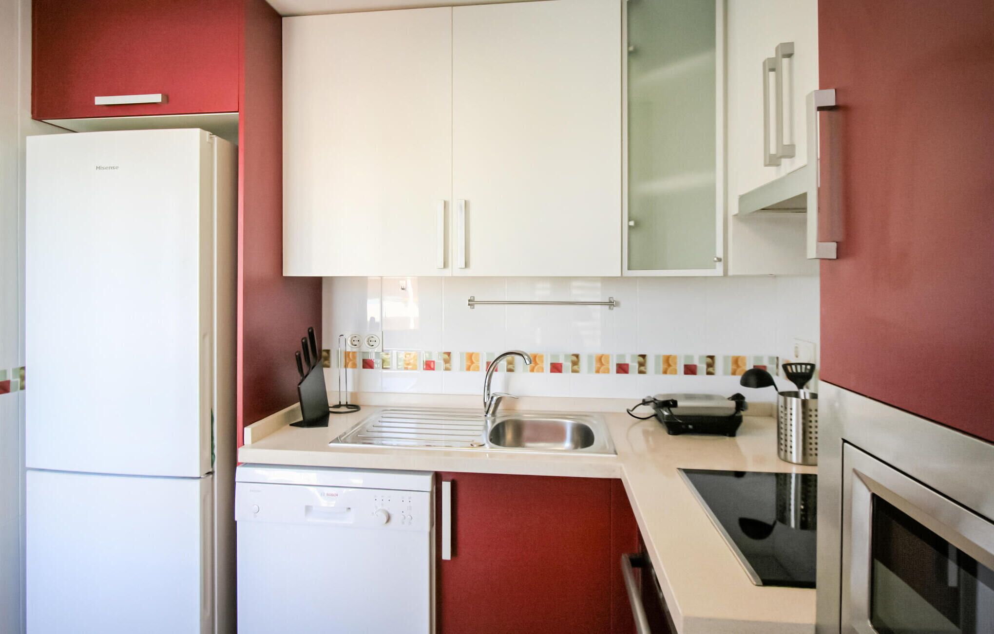 A compact kitchen with a white refrigerator, a Bosch dishwasher, a sink, and a stove.