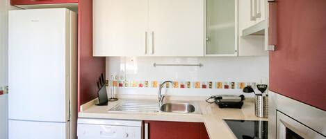 A compact kitchen with a white refrigerator, a Bosch dishwasher, a sink, and a stove.