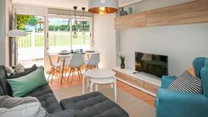 A modern living room with a sofa, a TV, and a dining area with chairs and a table. - Stunning apartment in Santa Pola (Santa Pola)