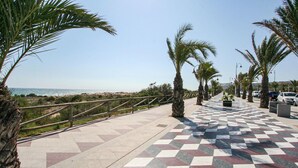 A paved walkway with a checkered pattern, lined with palm trees and a railing, leading towards a beach. - Stunning apartment in Santa Pola (Santa Pola)