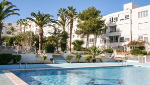 A swimming pool surrounded by palm trees and a white building with balconies. - Stunning apartment in Santa Pola (Santa Pola)