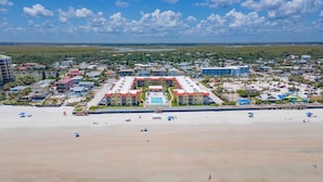 Ein Hotel direkt am Strand mit einem zentralen Pool, mehreren Gebäuden und einem Sandstrand.
