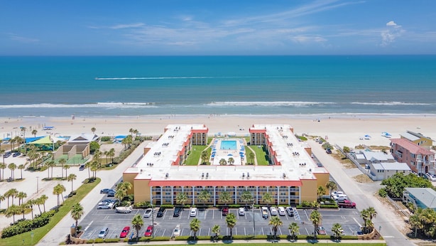 Ein Hotel mit Pool, Parkplatz und Blick auf den Strand.
