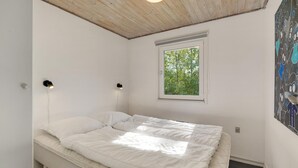 A bedroom with a bed, a window, and two wall-mounted lights.