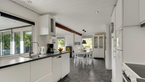 A modern kitchen with white cabinetry, a black countertop, and a stone tile floor. - Gorgeous home in Toftlund with WiFi (Toftlund)