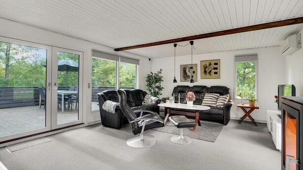 A spacious living room with a black leather sofa, a coffee table, and a dining area with a table and chairs.