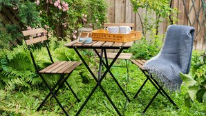 Uma mesa de madeira com um pote de vidro e uma caixa com a etiqueta 'Müller & Son' em um jardim.