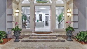 Una entrada imponente con un gran arco, una escultura decorativa de pez y dos plantas en macetas.