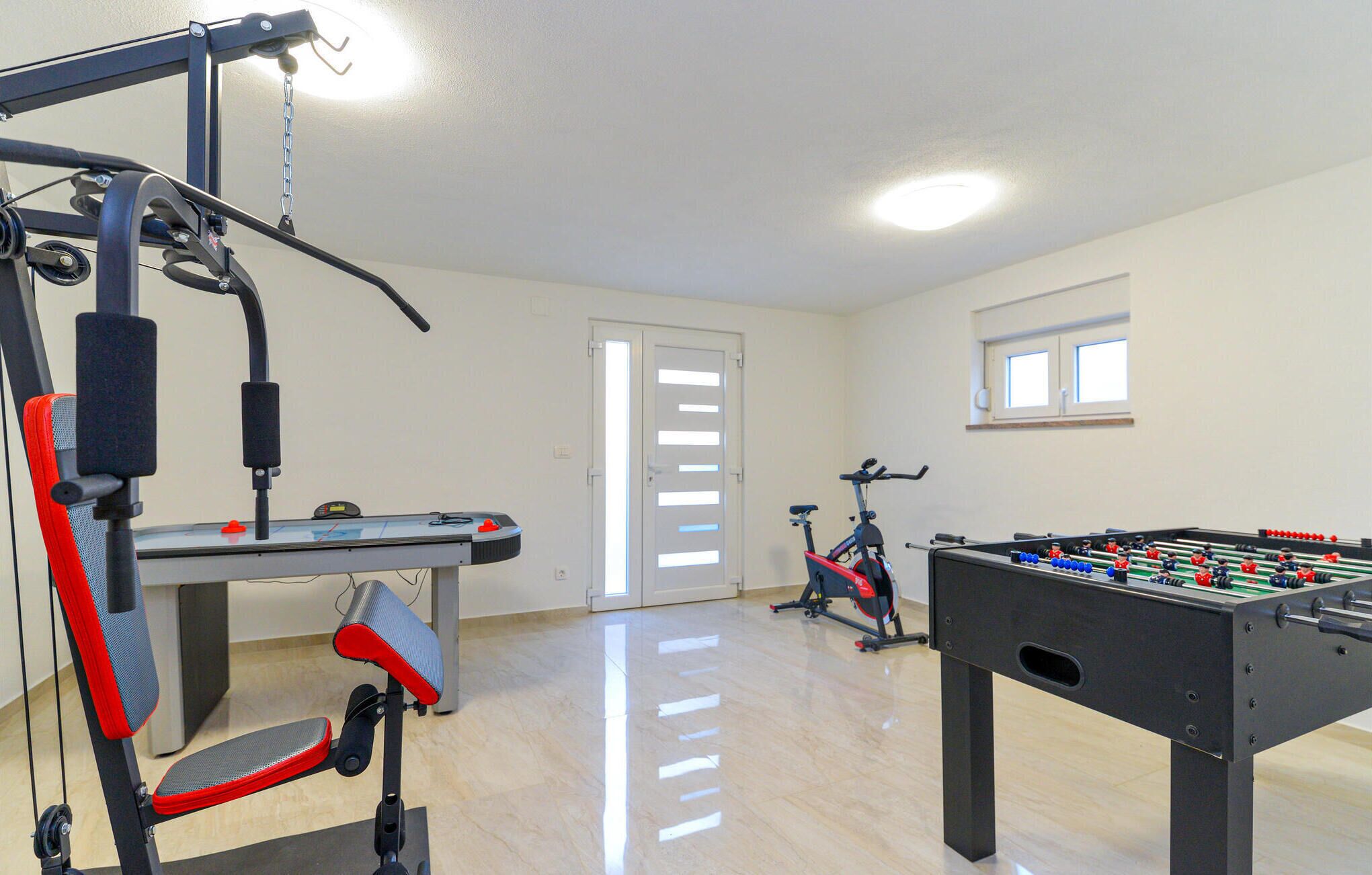 A gym with exercise equipment, a stationary bike, and a foosball table.