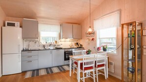 A compact kitchen with white cabinets, a microwave, a stove, and a dining area with a table and chairs. - 2 bedroom amazing home in åsensbruk (Åsensbruk)