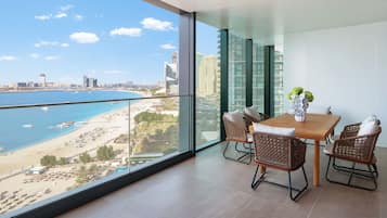 A balcony with a glass railing overlooking a beach and cityscape.