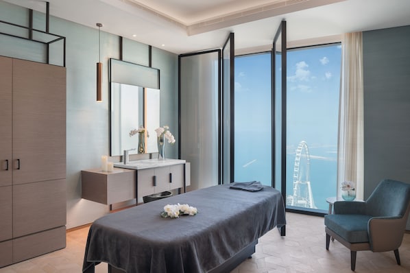 A modern hotel room with a large bed, a sitting area, a vanity with a mirror, and a view of a Ferris wheel. - Address Beach Resort (Dubai)