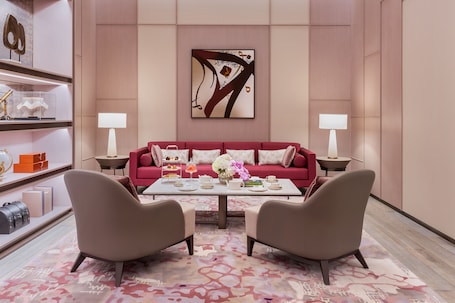 A modern living room with a red sofa, two armchairs, a coffee table, and decorative items.