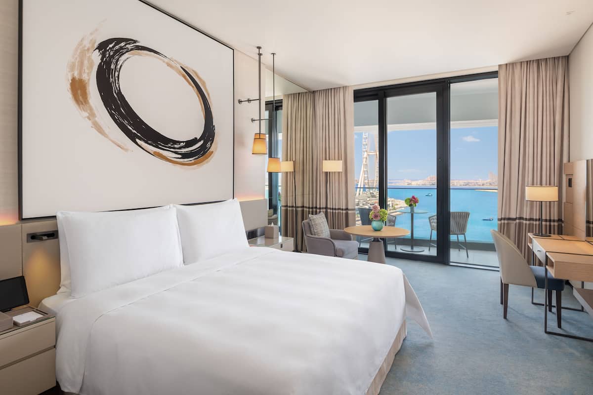 A hotel room with a large bed, a desk, and a view of the city and water.