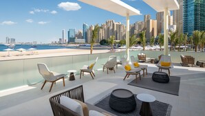A rooftop lounge with a city skyline view, outdoor seating, and a poolside area. - Address Beach Resort (Dubai)