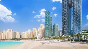 A beachfront hotel with modern architecture, a sandy beach, and a clear blue sky. - Address Beach Resort (Dubai)