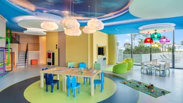 A modern children's playroom with a colorful ceiling, a round table with chairs, and a play mat with toys.
