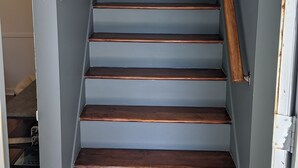 A staircase with wooden steps and a handrail, leading to a landing with a light fixture. - *New* The Foundry Getaway 2BR / 1 BR (Saranac Lake)