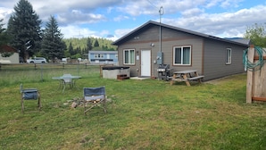A small cabin with a patio area, a grill, and a table with chairs.