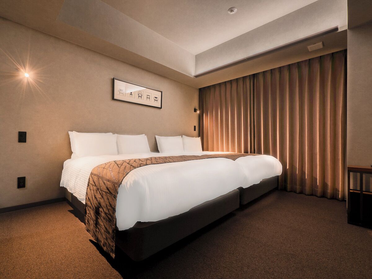 A hotel room with a large bed, a wall-mounted picture, and a curtain on the window.