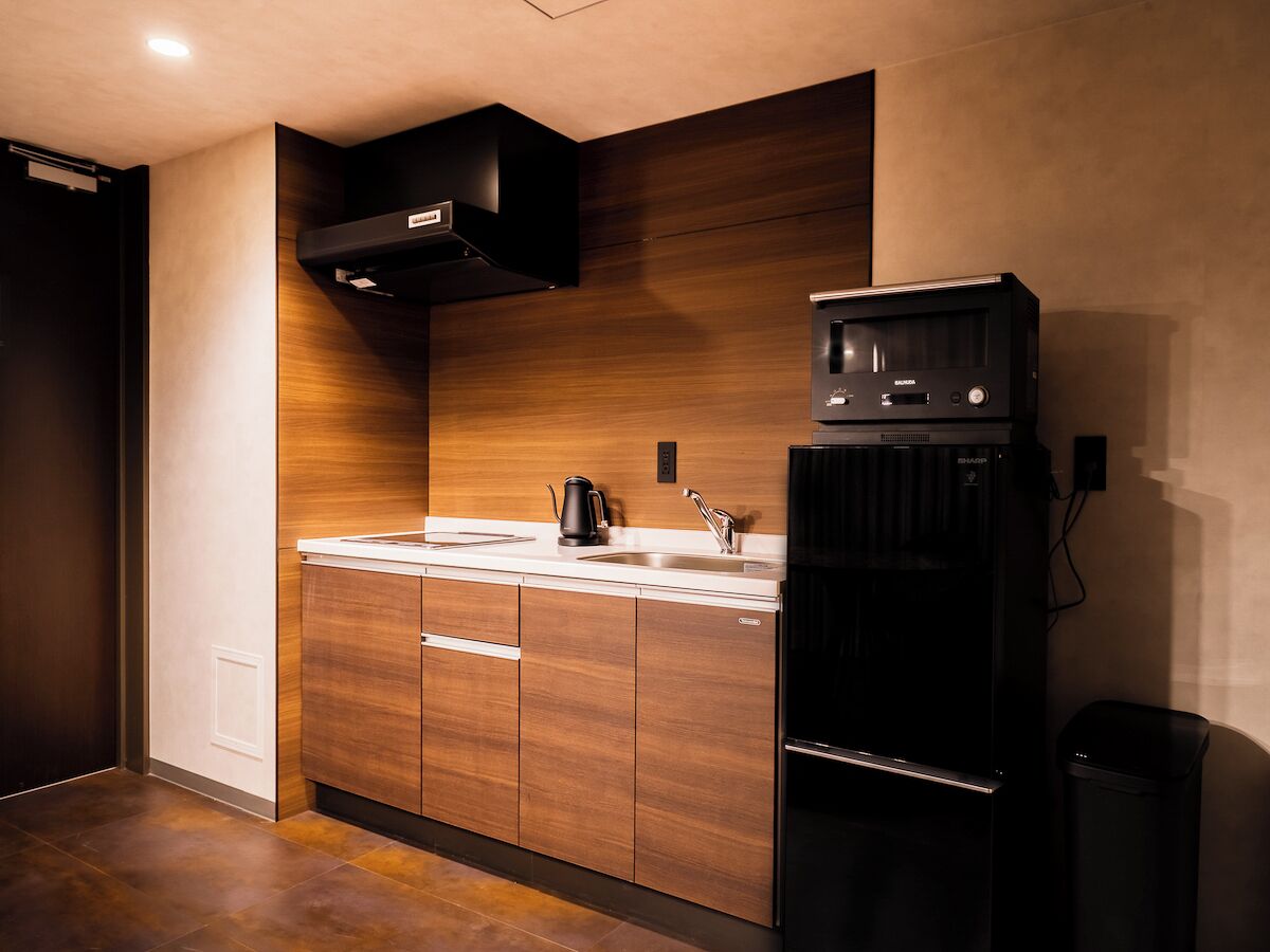A modern kitchen with wooden cabinets, a black refrigerator, and a built-in oven.