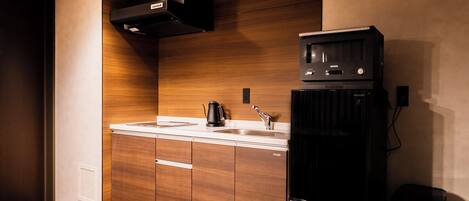 A modern kitchen with wooden cabinets, a black refrigerator, and a built-in oven.