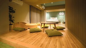 Een moderne hotelkamer met een houten vloer, een bank, een eettafel en een bed.