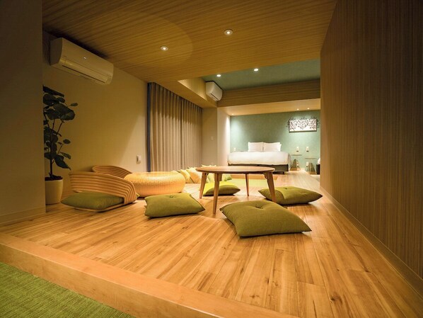 A modern hotel room with a wooden floor, a sofa, a small table, and a bed.
