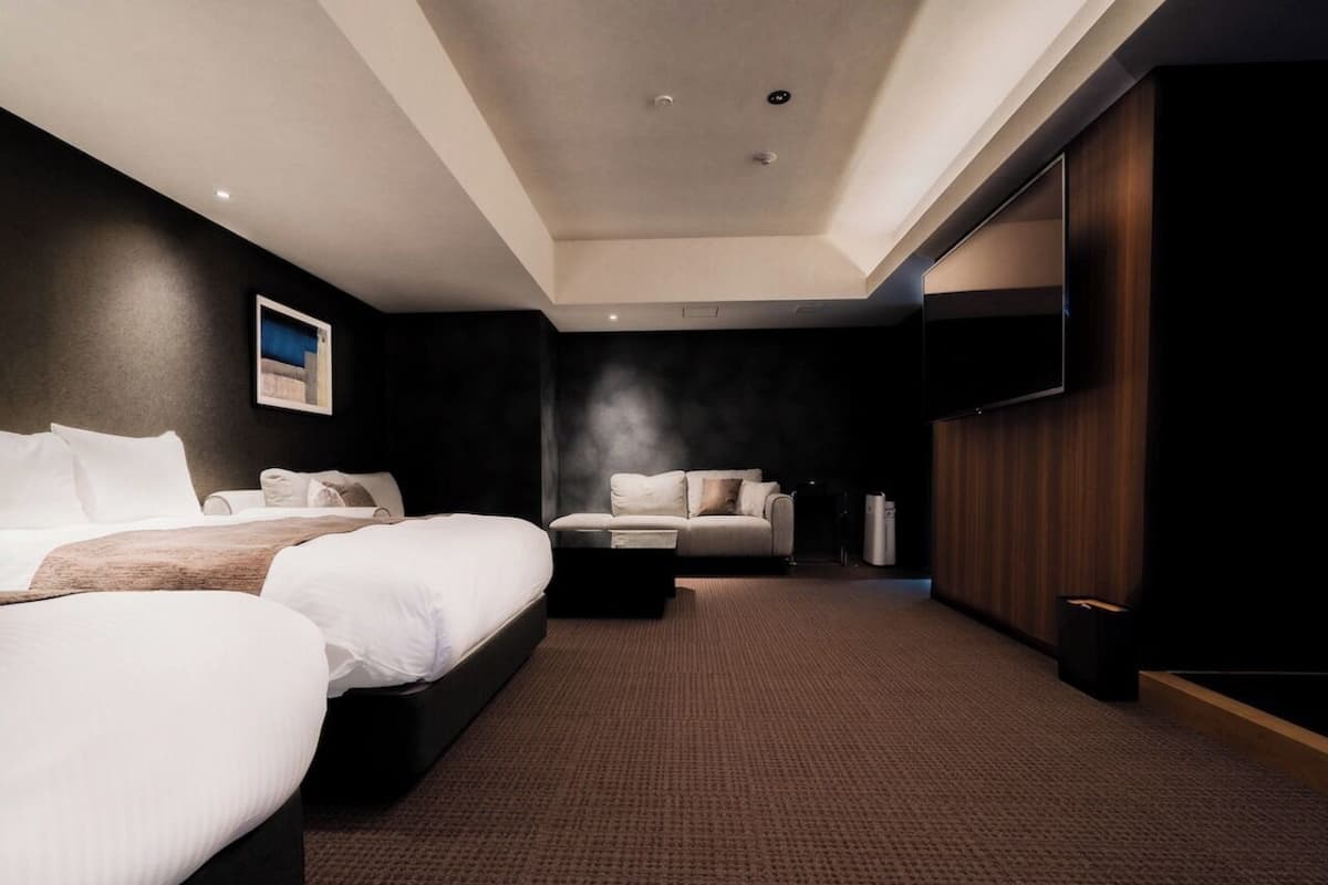 Habitación de hotel con dos camas, un sofá, una mesa de centro y un espejo grande.