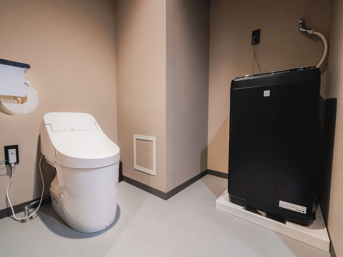 Un bagno con un water bianco, uno scaldabagno nero e un box doccia in vetro.