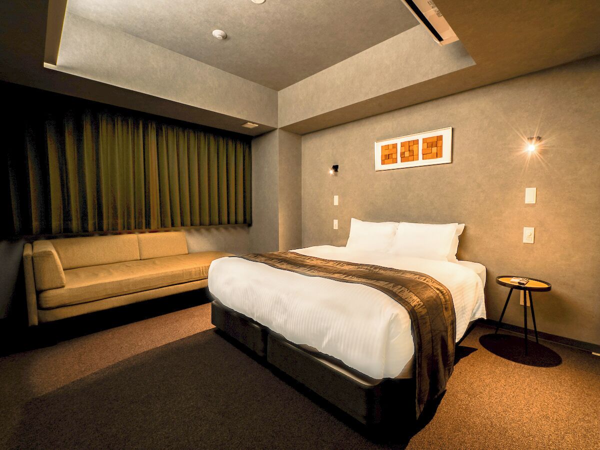 A modern hotel room with a large bed, a sofa, and a small table.
