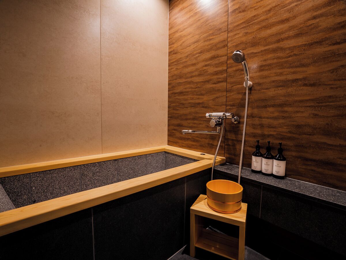 Un bagno moderno con una vasca da bagno in legno, uno sgabello di legno e uno scaffale con bottiglie.