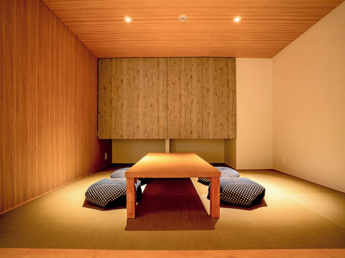 Una habitación con techo de madera, una mesa central y dos cojines estampados en el suelo.